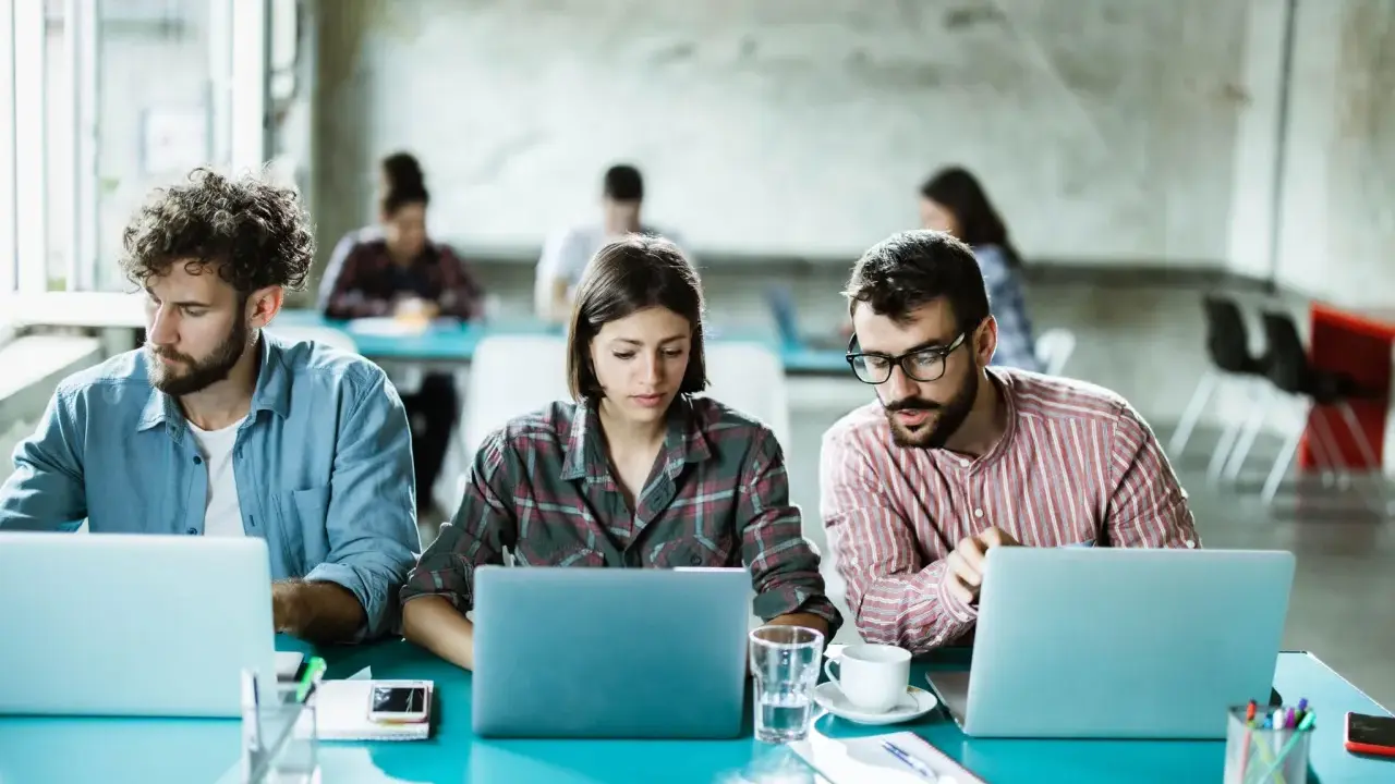 Ludzie pracują przy laptopach, tworząc ład organizacyjny w nowoczesnym biurze.