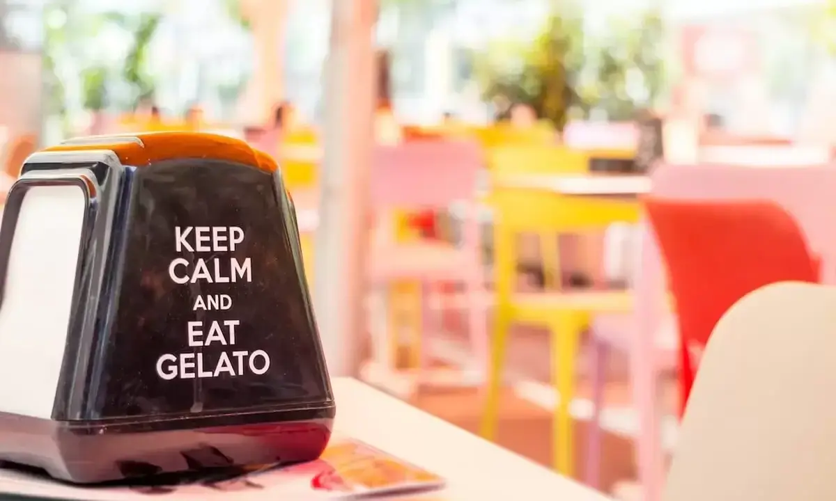 Na serwetniku napis: "Keep calm and eat gelato". W tle kolorowe krzesła, idealne na letnie hasła promocyjne.