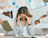 Kobieta z rękami na skroniach, przytłoczona zadaniami. Brak organizacji pracy własnej prowadzi do stresu i chaosu.