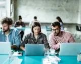 Ludzie pracują przy laptopach, tworząc ład organizacyjny w nowoczesnym biurze.