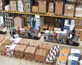 Magazynierzy w akcji, kompletacja jednostopniowa zamówień. Wózki widłowe i palety z elektroniką.