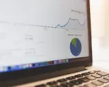 Analiza ankiety na ekranie laptopa: wykres liniowy i kołowy pokazują dane.