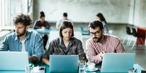 Ludzie pracują przy laptopach, tworząc ład organizacyjny w nowoczesnym biurze.