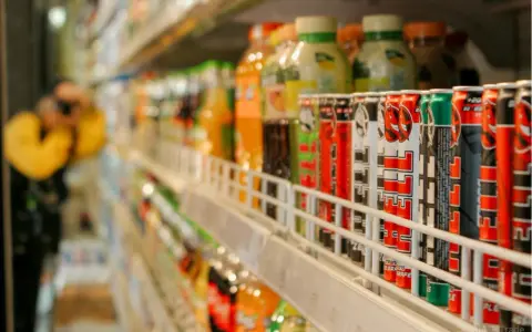 Rząd puszek z napojami energetycznymi na półce sklepowej, część branży FMCG.