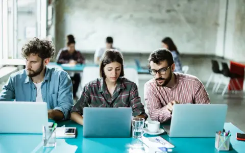 Ludzie pracują przy laptopach, tworząc ład organizacyjny w nowoczesnym biurze.