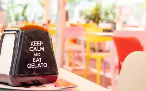 Na serwetniku napis: "Keep calm and eat gelato". W tle kolorowe krzesła, idealne na letnie hasła promocyjne.