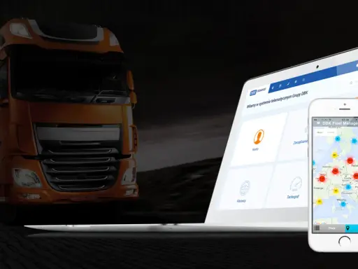 Pomarańczowa ciężarówka obok laptopa i telefonu z mapą pokazującą lokalizację pojazdów dzięki systemowi GPS.