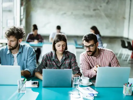 Ludzie pracują przy laptopach, tworząc ład organizacyjny w nowoczesnym biurze.