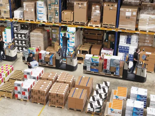 Magazynierzy w akcji, kompletacja jednostopniowa zamówień. Wózki widłowe i palety z elektroniką.