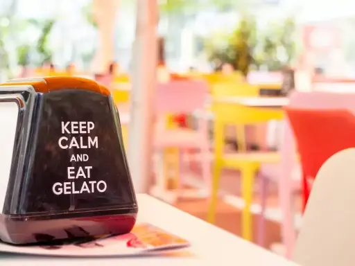 Na serwetniku napis: "Keep calm and eat gelato". W tle kolorowe krzesła, idealne na letnie hasła promocyjne.