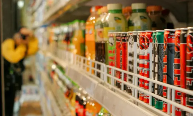 Rząd puszek z napojami energetycznymi na półce sklepowej, część branży FMCG.