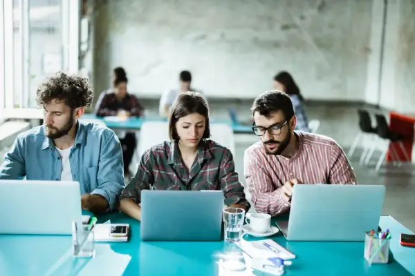 Ludzie pracują przy laptopach, tworząc ład organizacyjny w nowoczesnym biurze.